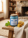 Candle jar labeled 'Alert & Energized' on a wooden stool with honeycomb and mint leaves in a cozy room.