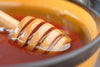 Honey dipper in a bowl of honey with a blurred background