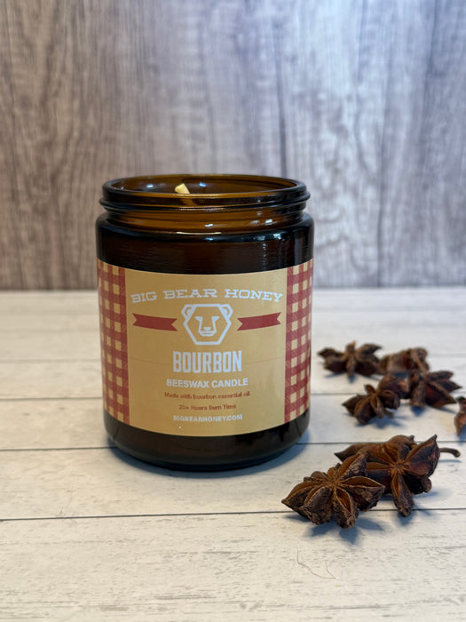 Bourbon scented candle in a glass jar with a label on a wooden surface, surrounded by star anise.
