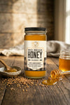 Jar of Big Bear Honey on a wooden surface with honeycomb pieces and a spoon.