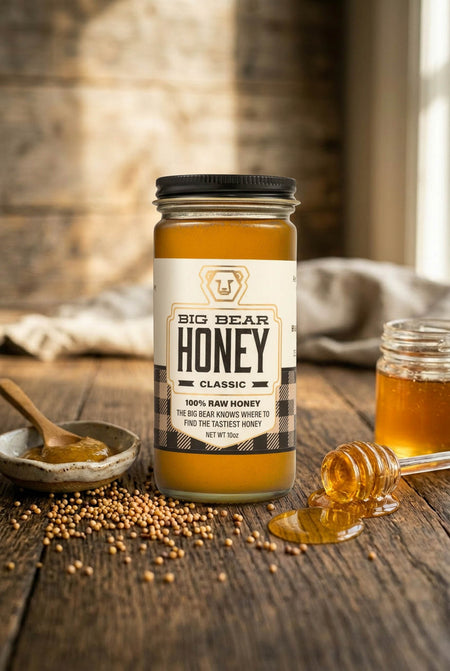 Jar of Big Bear Honey on a wooden surface with honeycomb pieces and a spoon.