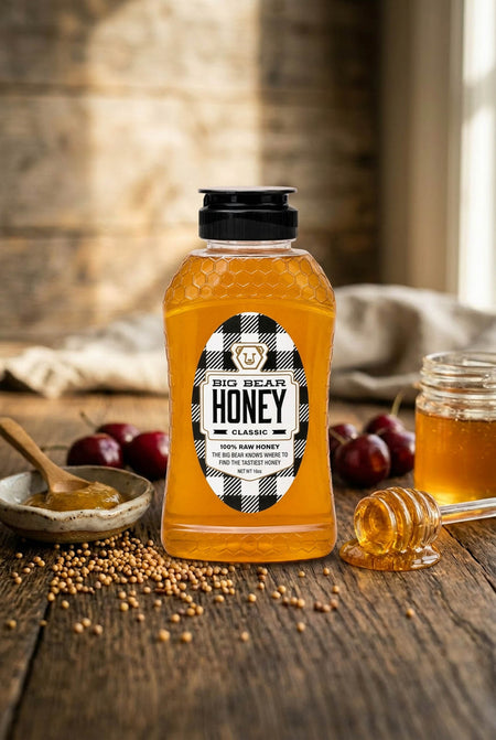 Bottle of Big Bear Honey on a wooden table with honeycomb pieces and plums.