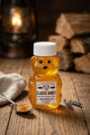 Bear-shaped honey jar with a label on a wooden surface with a warm background.