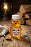 Bear-shaped honey jar with a label on a wooden surface with a warm background.