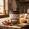 Chocolate Creamed honey jar on rustic wood table with cocoa and honeycomb surrounding it.