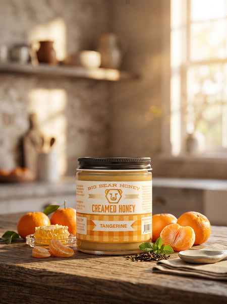 Jar of Big Bear Honey Tangerine Creamed Honey on a wooden table with tangerines in a kitchen setting.