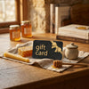 Gift card with a bow on a wooden table with honey jars and a honey dipper.