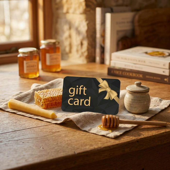 Gift card with a bow on a wooden table with honey jars and a honey dipper.