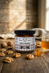 Jar of Big Bear Honey Coated Walnuts on a wooden surface with honey and walnuts.