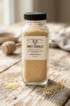 Jar of honey granules on a wooden surface with a blurred background