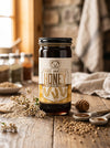 Jar of Big Bear Honey Buckwheat on a wooden table with honeycomb and jars in the background
