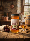 Big Bear Honey Cherry Whiskey bottle on a wooden table with a glass of whiskey and honeycomb.