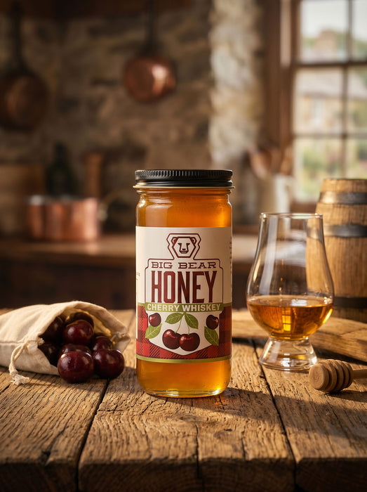 Big Bear Honey Cherry Whiskey bottle on a wooden table with a glass of whiskey and honeycomb.