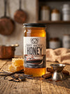 Jar of Big Bear Honey Rum Infused on a wooden surface with honeycomb and cinnamon sticks.