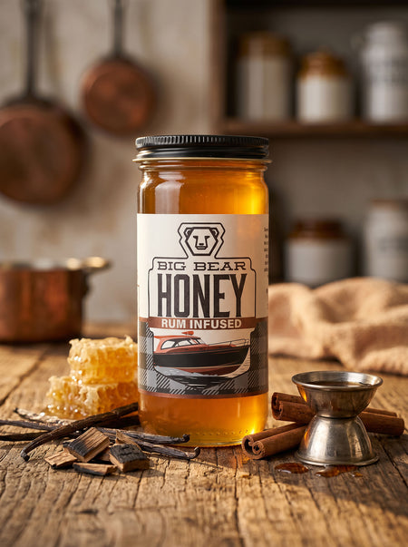Jar of Big Bear Honey Rum Infused on a wooden surface with honeycomb and cinnamon sticks.