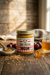 Jar of Honey Mustard with cherry flavor on a wooden table with honey and mustard seeds.