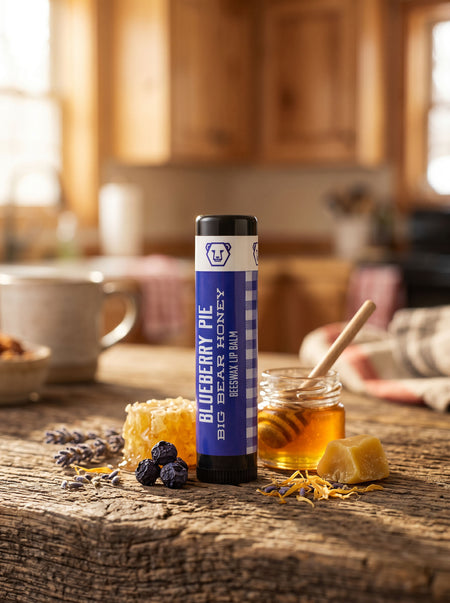 Blueberry Pie Big Bear Honey lip balm on a wooden table with honey and lavender.