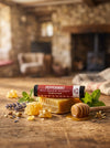 Peppermint lip balm with honeycomb and honey on a wooden surface in a cozy room.