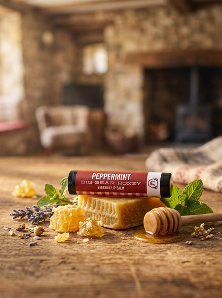 Peppermint lip balm with honeycomb and honey on a wooden surface in a cozy room.