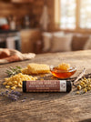 Lip balm with Tahitian Vanilla and Big Bear Honey on a wooden table with honeycomb and lavender.