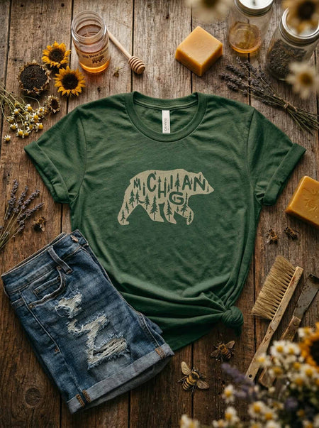 Green t-shirt with bear graphic and 'Michigan' text on a wooden surface with rustic items.