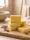 Yellow soap bars on a wooden board with almonds and lavender flowers.