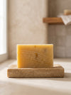 Bar of soap on a wooden soap dish with a neutral background
