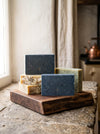 Five bars of soap on a wooden stand with a neutral background