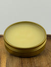 Open tin of balm on wooden surface.