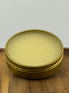 Open tin of balm on wooden surface.