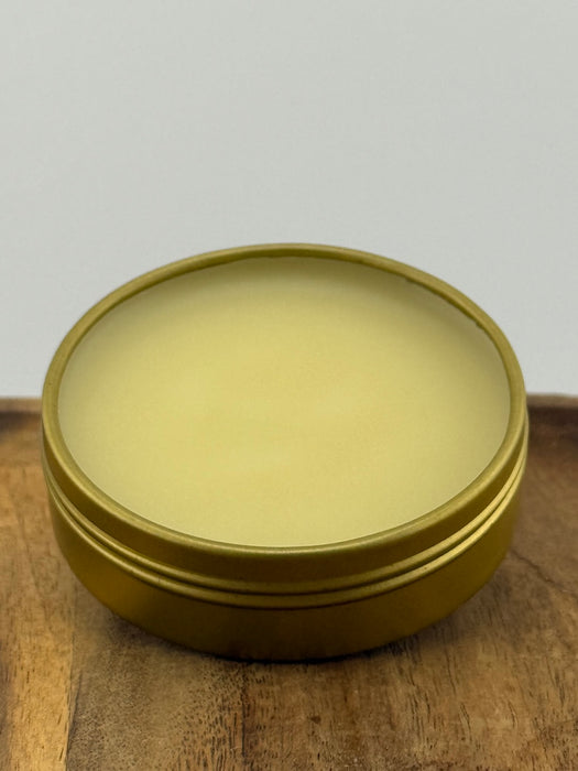 Open tin of balm on wooden surface.